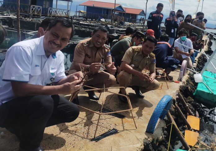 General Manager PT ANTAM Tbk UBPN Kolaka, Nilus Rahmat bersama aparat pemerintah daerah mengikat bibit karang pada acara transplantasi terumbu karang di perairan desa Hakatutobu, Senin (11/7/2022).